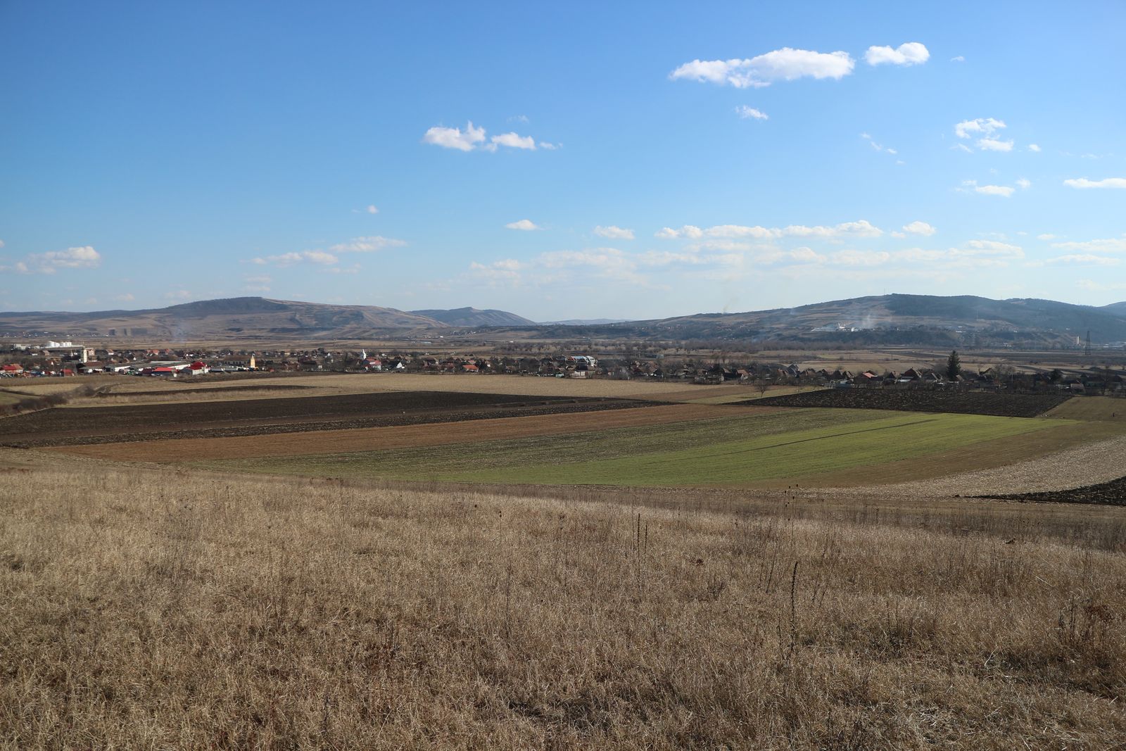 Războieni-Cetate. Blick auf den Fundplatz im Mureştal. Das Lager liegt im Stoppelfeld am Rand des Dorfes, auf den umliegenden Flächen bis an den Rand des Hügels im Vordergrund befanden sich damals der vicus und die ersten Ausläufer der ländlichen Besiedlung.