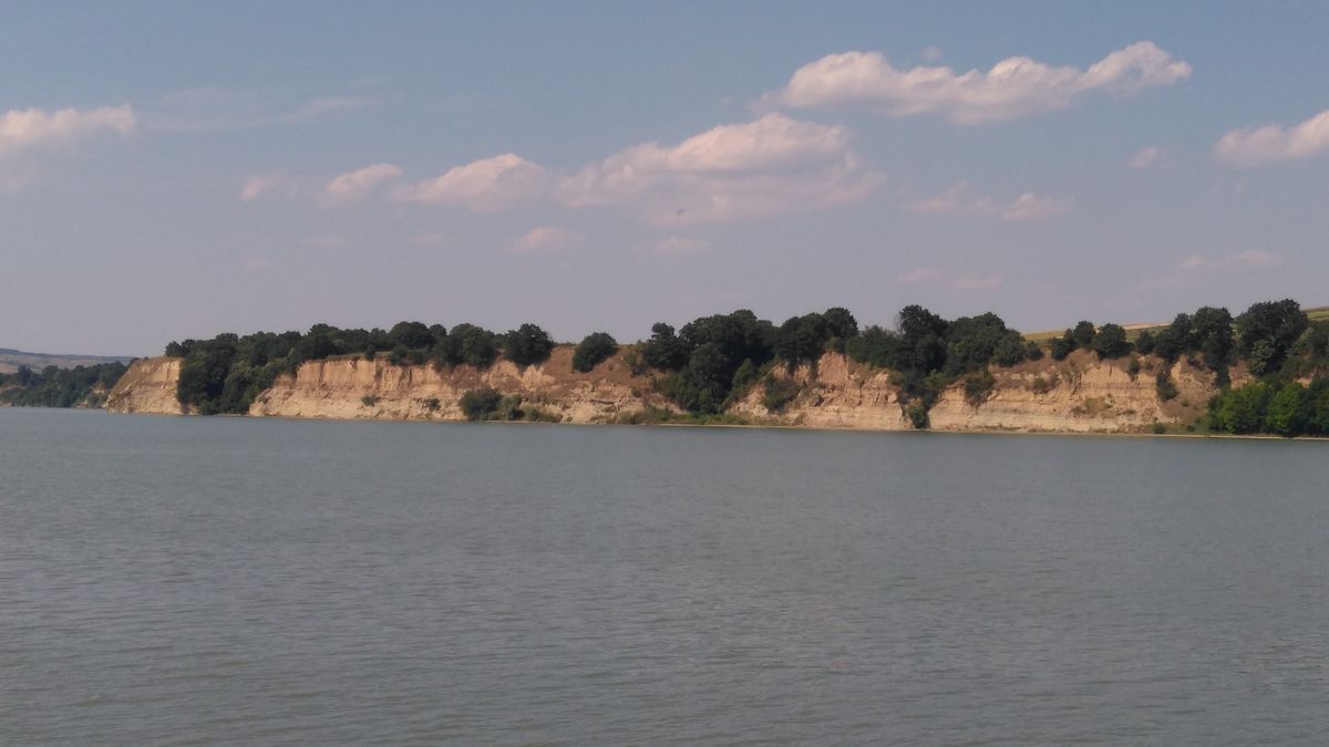 Pâncești: Blick über den Lacul Berești auf die dakische Festung Răcătău. Im Lößprofil außerdem gut zu sehen: Die Bodenbildung der Eem-Warmzeit.