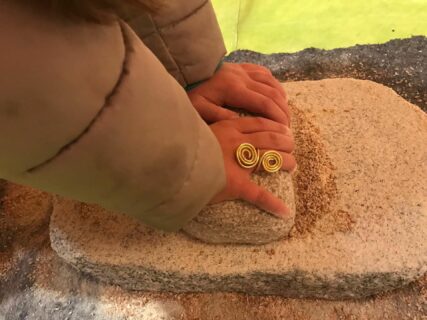 Ein Besucher mahlt Getreide zu Mehl und trägt dabei stolz seinen selbstgemachten Fingerring.